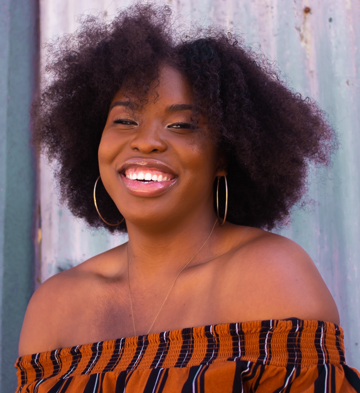 A black woman smiling at the camera with natural curly hair